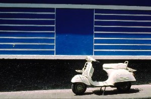 white vespa in front of colorful housefacades